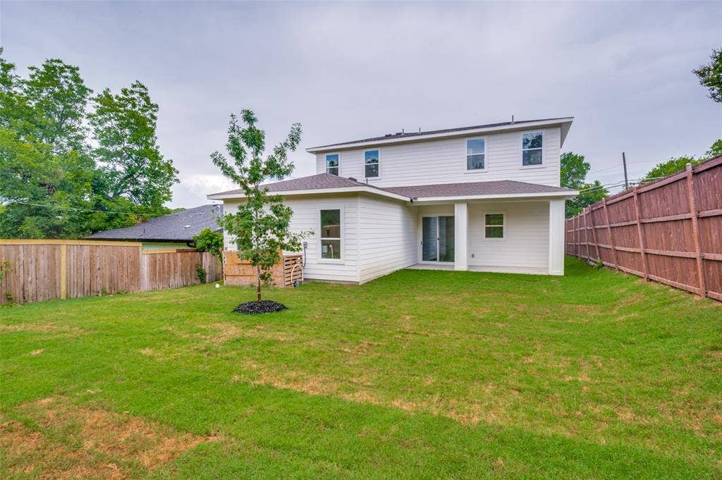 1511 Morrell Avenue, Dallas, TX 75203 Expansive backyard with a manicured lawn, a young tree, and privacy fencing