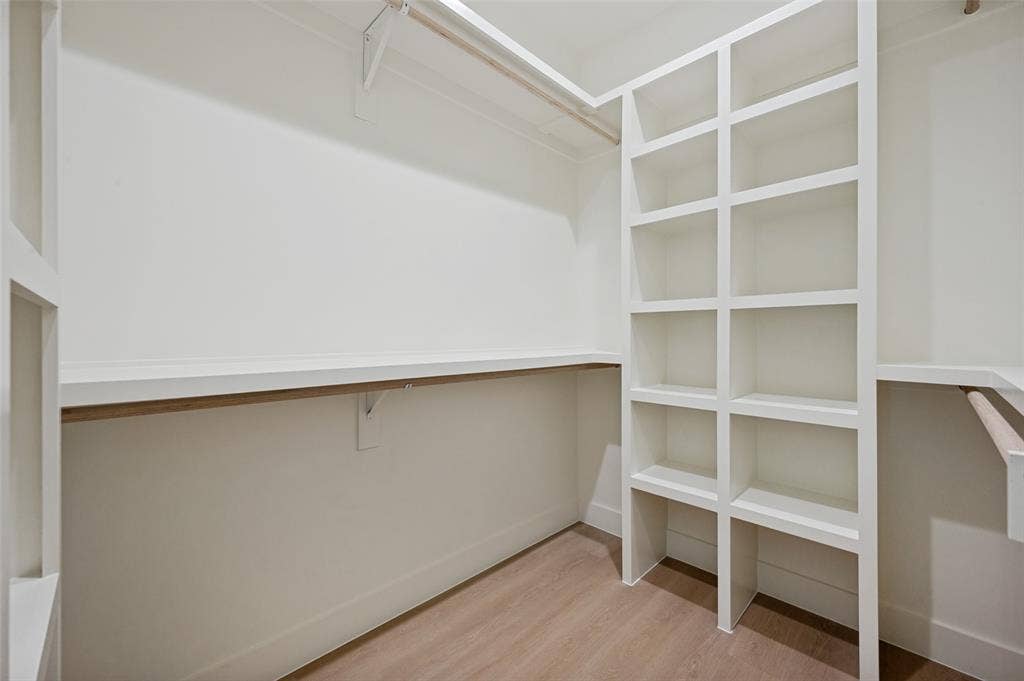 1511 Morrell Avenue, Dallas, TX 75203 Custom built-in shelving, white painted walls, wood-finish flooring, and integrated hanging rods