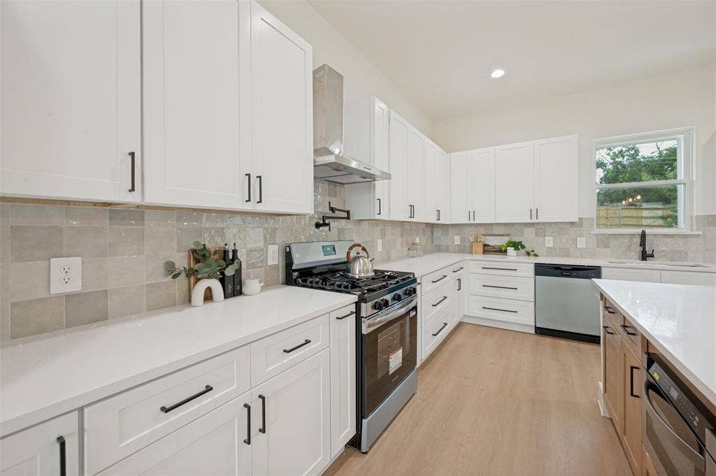 1511 Morrell Avenue, Dallas, TX 75203 Contemporary kitchen featuring white cabinetry, light-toned countertops, a stainless steel range with a ventilation hood, and light-colored tile backsplash