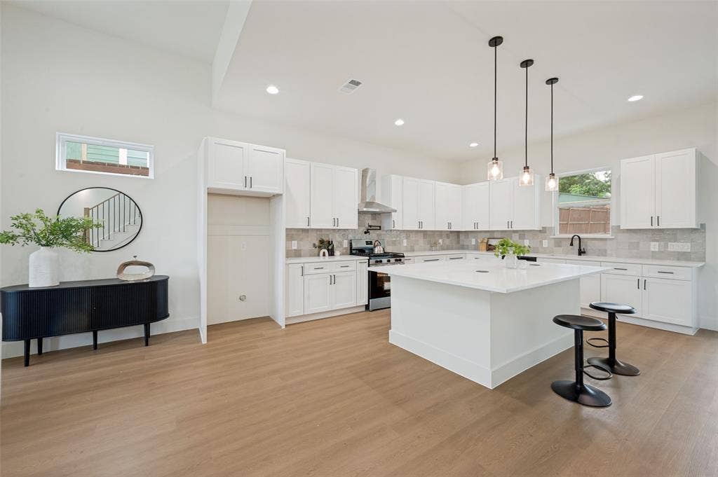 1511 Morrell Avenue, Dallas, TX 75203 Spacious kitchen featuring an expansive island with a light-toned countertop, white cabinetry with dark hardware, and a tile backsplash