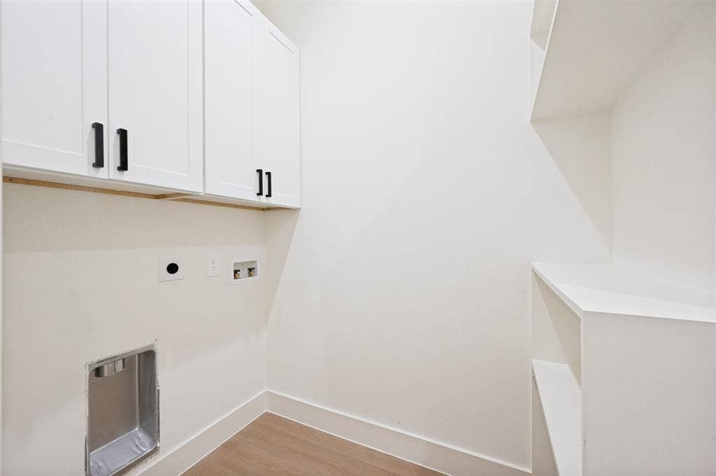 1511 Morrell Avenue, Dallas, TX 75203 White cabinetry with black hardware, built-in shelving, light wood-finish flooring, and white walls