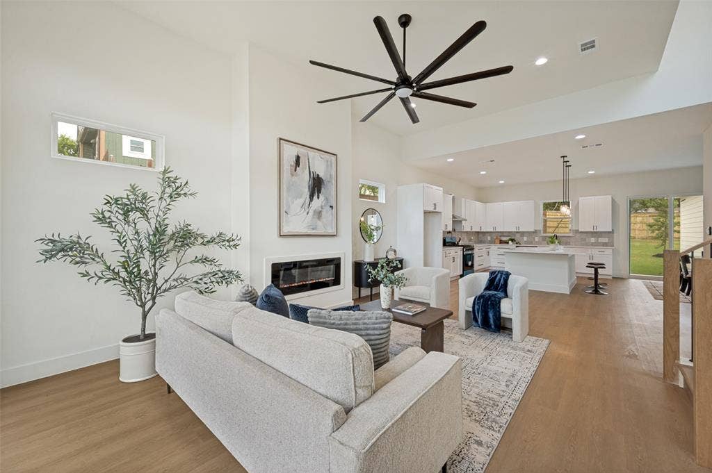 1511 Morrell Avenue, Dallas, TX 75203 Vaulted ceilings, wood-finish flooring, a modern linear fireplace, and a kitchen featuring white cabinetry with a central island and pendant lighting