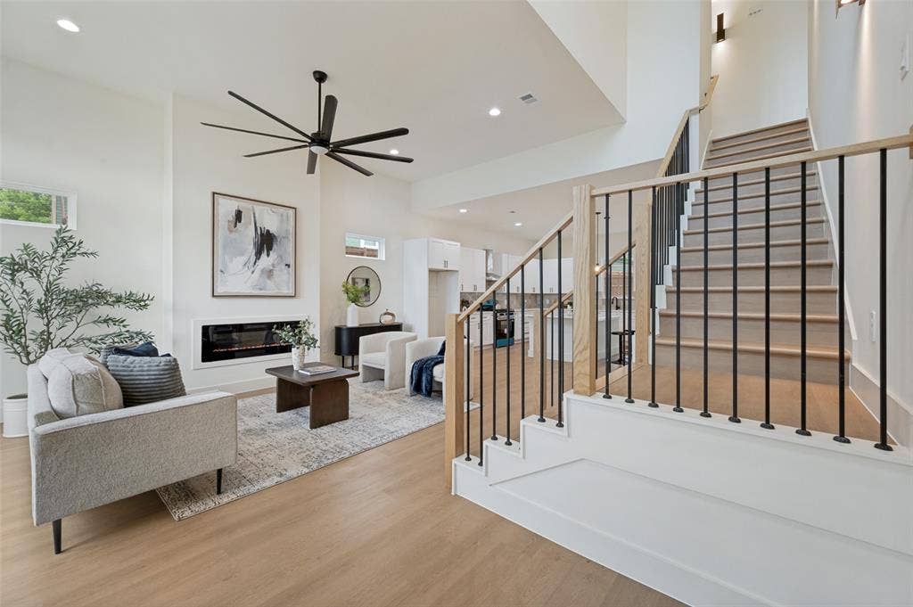 1511 Morrell Avenue, Dallas, TX 75203 Vaulted ceiling, built-in linear fireplace, wood-finish flooring, staircase with black metal balusters and wood handrail, and recessed lighting