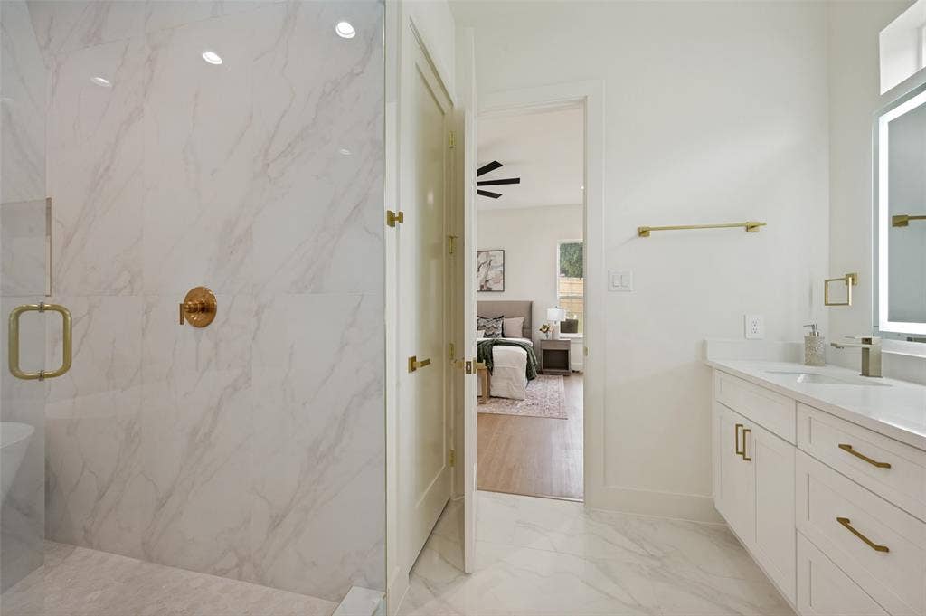 1511 Morrell Avenue, Dallas, TX 75203 Glass-enclosed shower with gold-tone fixtures and marble-look tile
