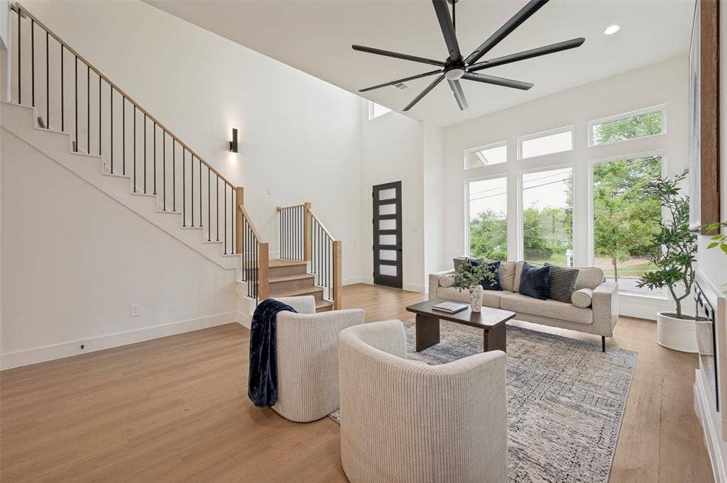 1511 Morrell Avenue, Dallas, TX 75203 Two-story entry featuring wood-finish flooring, a modern staircase with wood handrails and black metal balusters, a large ceiling fan, and expansive windows