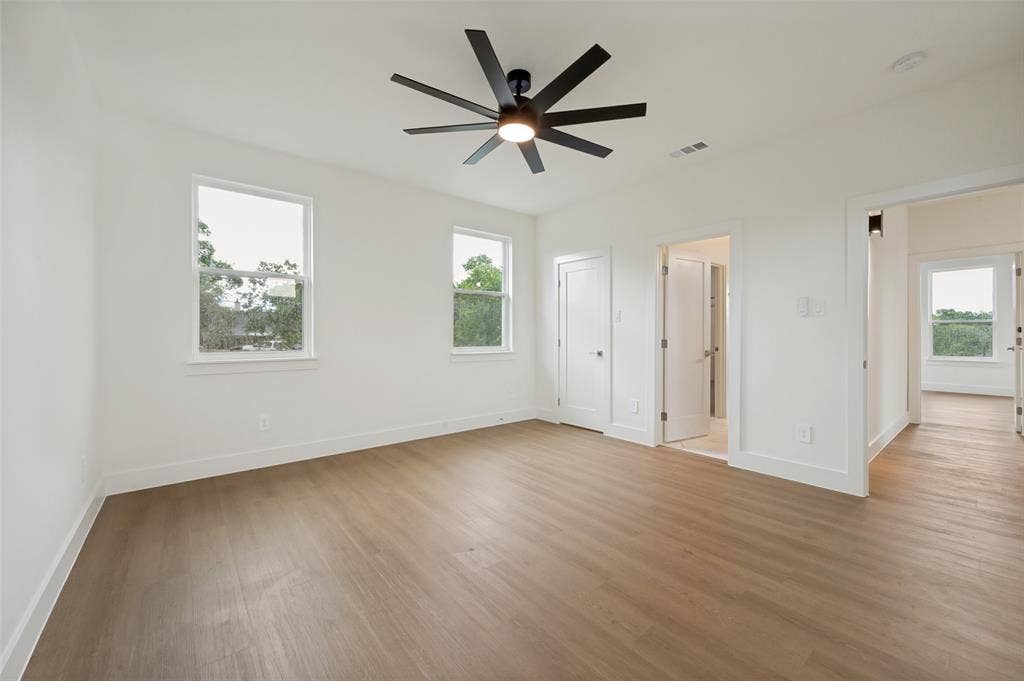 1511 Morrell Avenue, Dallas, TX 75203 Light-filled interior featuring two windows, wood-finish flooring, a modern ceiling fan, and white painted walls
