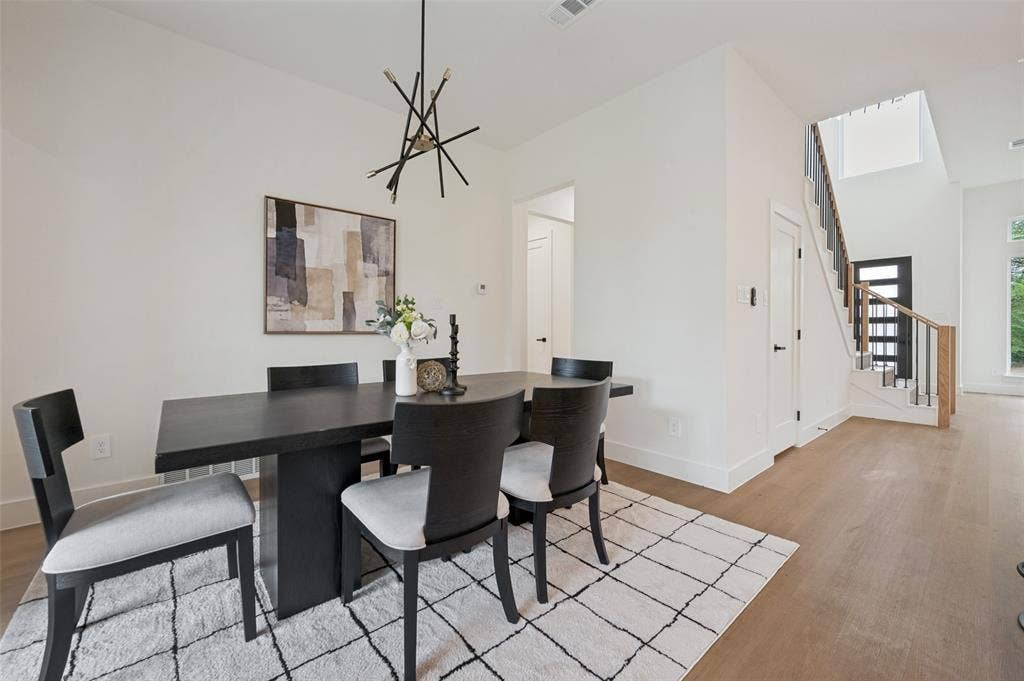 1511 Morrell Avenue, Dallas, TX 75203 Open-concept living area featuring a modern chandelier, light wood-finish flooring, and a contemporary staircase with wood and metal railing