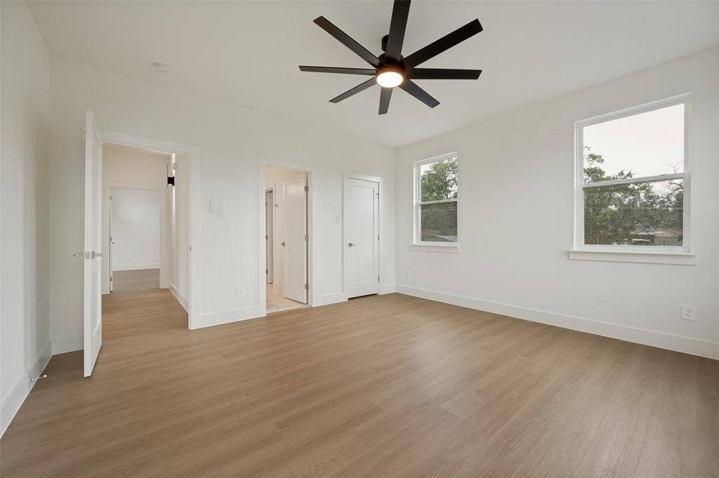 1511 Morrell Avenue, Dallas, TX 75203 Spacious room featuring light wood-finish flooring, a modern black ceiling fan, and multiple windows