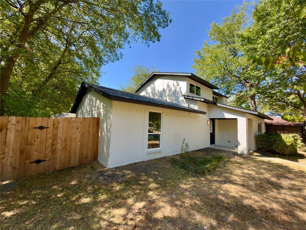 1834 Caldwell, Garland, TX 75041 Contemporary exterior featuring white painted brick, a black shingle roof, a wood privacy fence, and a covered entry