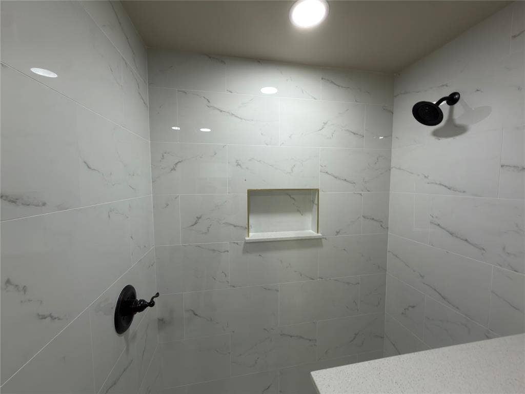 1834 Caldwell, Garland, TX 75041 Shower featuring white tile with gray veining, a built-in shower niche, matte black shower fixtures, and recessed lighting