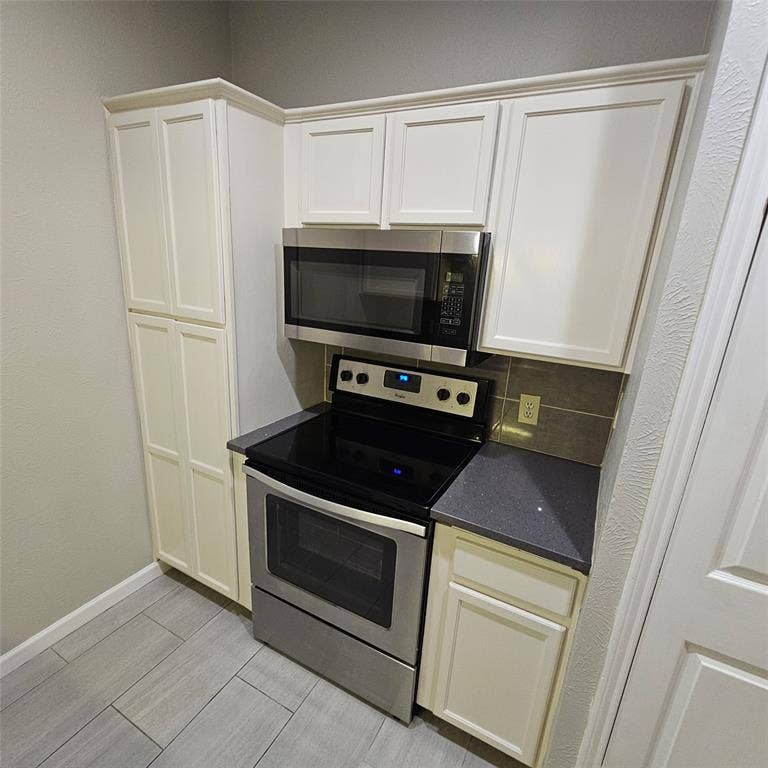 9600 ROYAL, #612, Dallas, TX 75243 Kitchen with stainless steel appliances, tasteful backsplash, dark stone counters, and wood finish floors