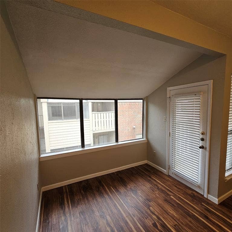 9600 ROYAL, #612, Dallas, TX 75243 Spare room featuring vaulted ceiling and dark wood-style floors
