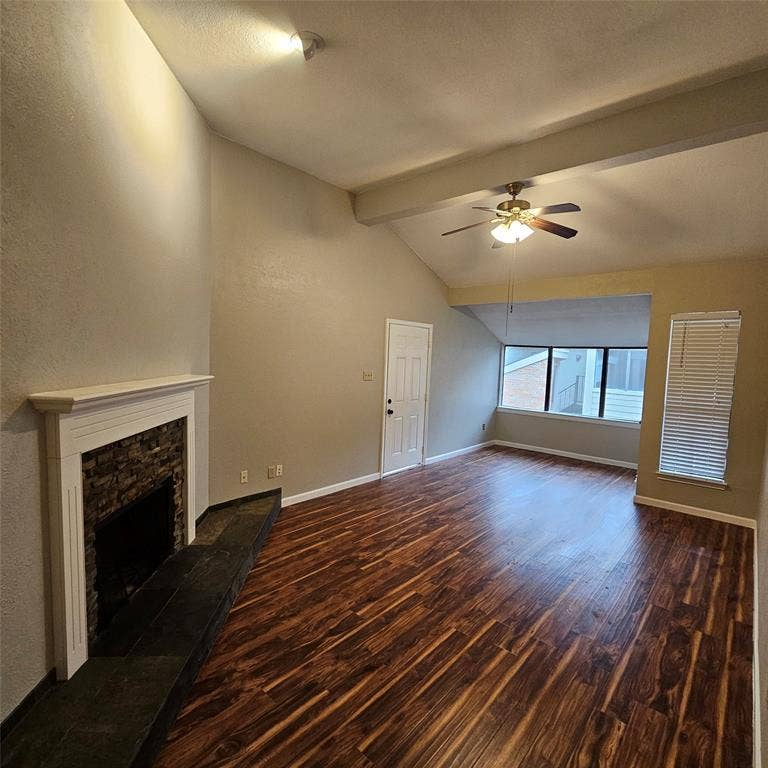 9600 ROYAL, #612, Dallas, TX 75243 Unfurnished living room with wood finished floors, ceiling fan, a fireplace, and a textured wall