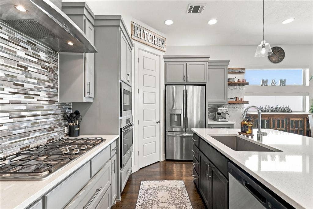 Designer touches, stainless appliances, and ample cabinetry give this kitchen a contemporary look