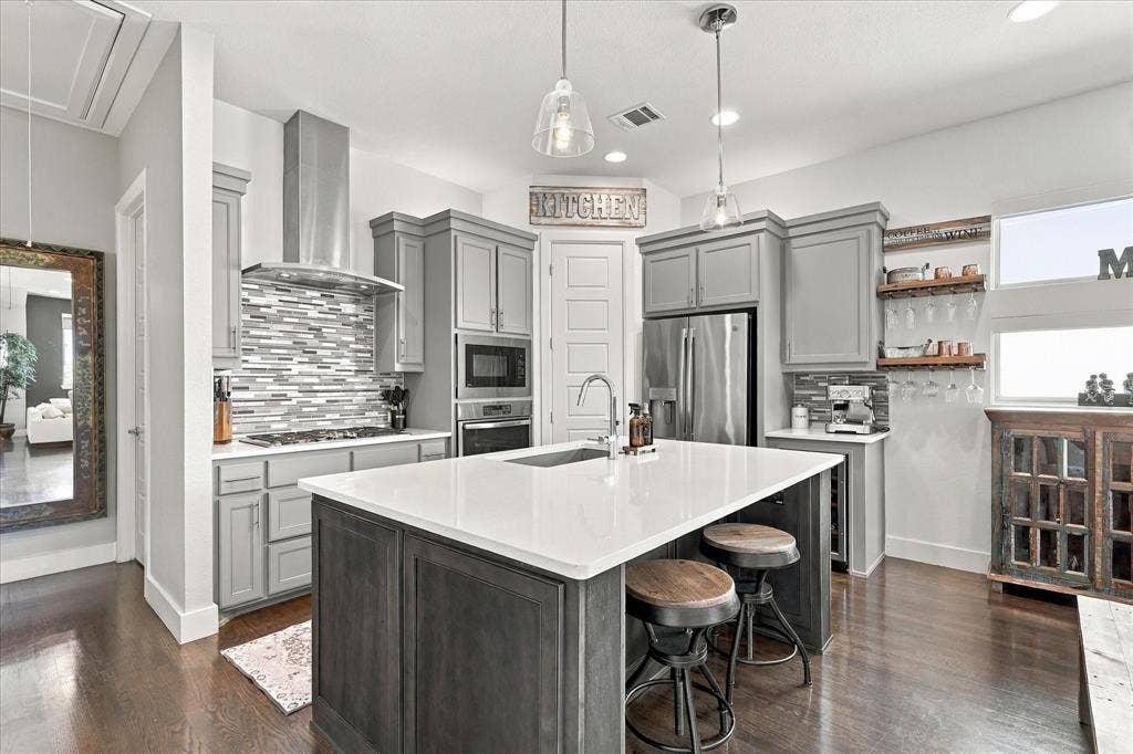 The kitchen has stainless steel appliances, gas stovetop, designer island, quartz countertops and wine fridge for easy entertaining!