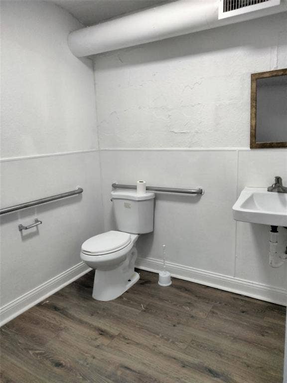 513 N 4th Street, Princeton, TX 75407 Wall-mounted sink with chrome faucet, wood-finish flooring, and white wainscoting