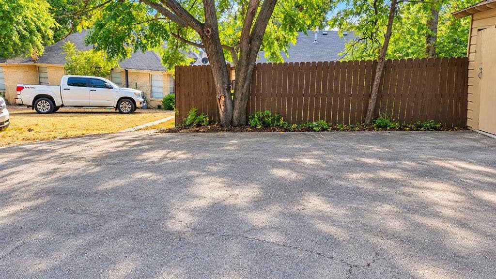 914 Harlandale Avenue, Dallas, TX 75216 Paved driveway with mature trees, established landscaping, and a privacy fence