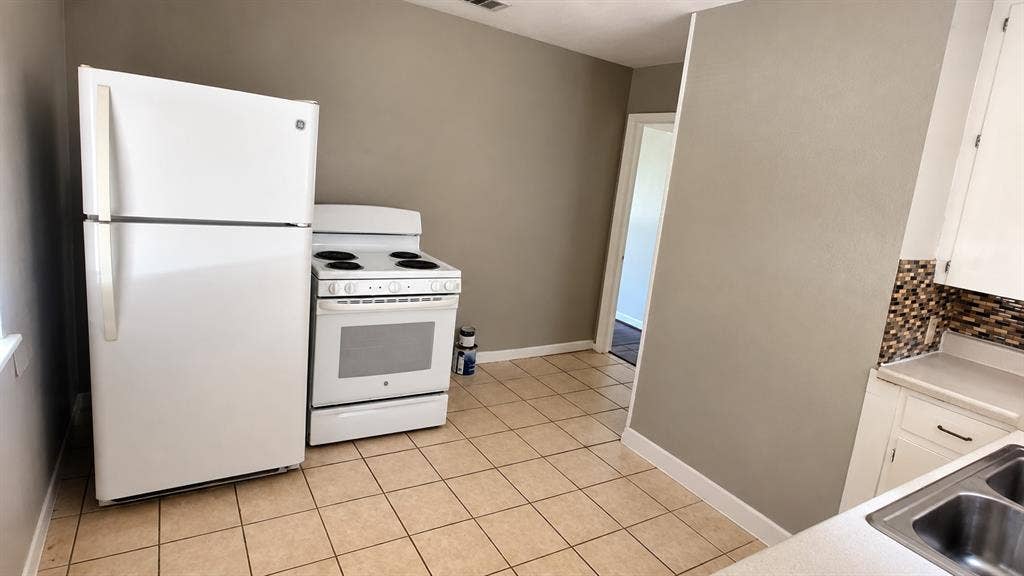 914 Harlandale Avenue, Dallas, TX 75216 Kitchen featuring tile flooring, white cabinetry, a dual basin stainless steel sink, and a mosaic tile backsplash