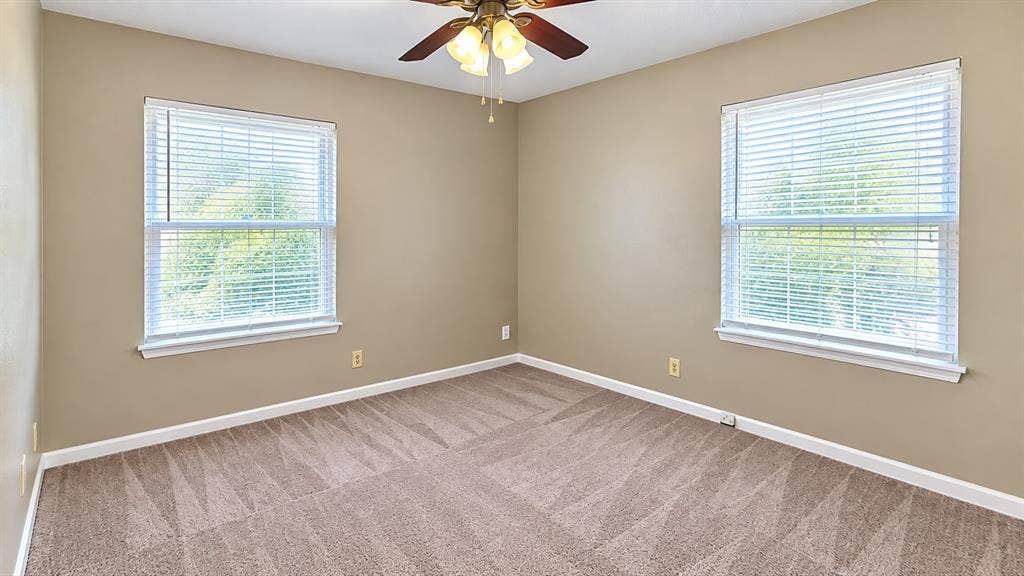 914 Harlandale Avenue, Dallas, TX 75216 Neutral wall paint, two windows with blinds, ceiling fan with light fixture, and patterned carpet flooring