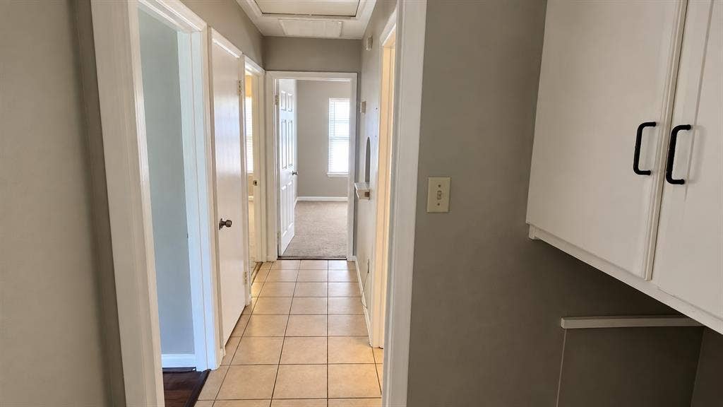 914 Harlandale Avenue, Dallas, TX 75216 Hallway featuring tile flooring, painted walls, white trim, and built-in white cabinetry with dark pull handles