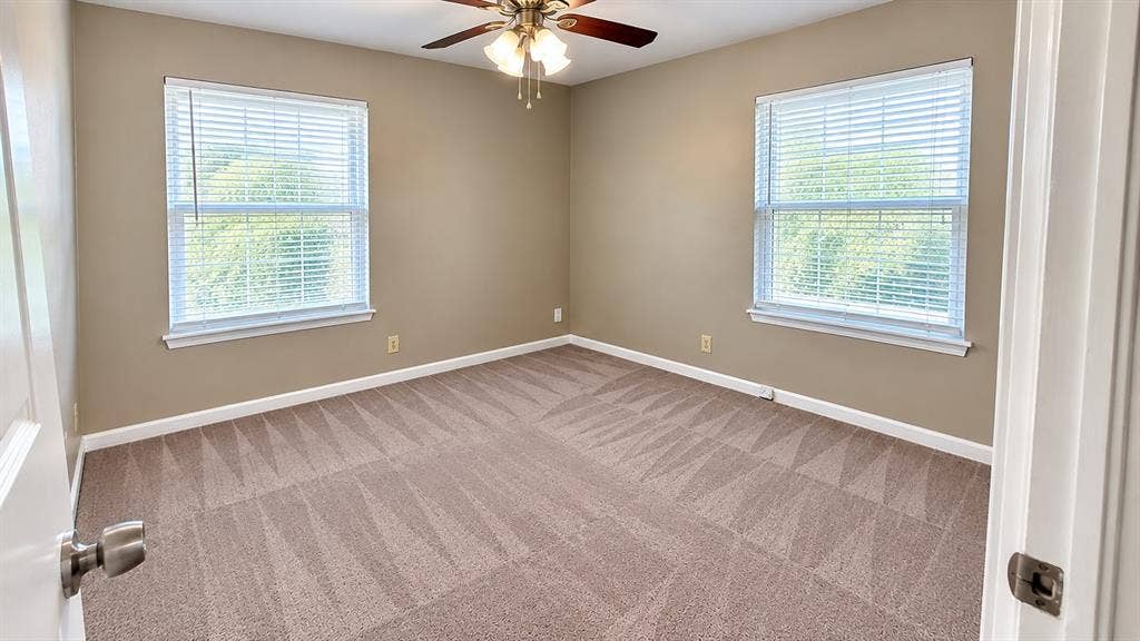 914 Harlandale Avenue, Dallas, TX 75216 Neutral tone wall paint, dual windows with blinds, patterned carpet flooring, and a ceiling fan with integrated lighting