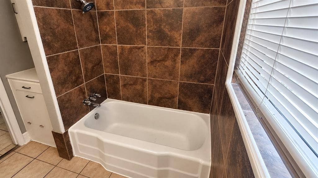 914 Harlandale Avenue, Dallas, TX 75216 Built-in bathtub with shower head, surrounded by brown tile