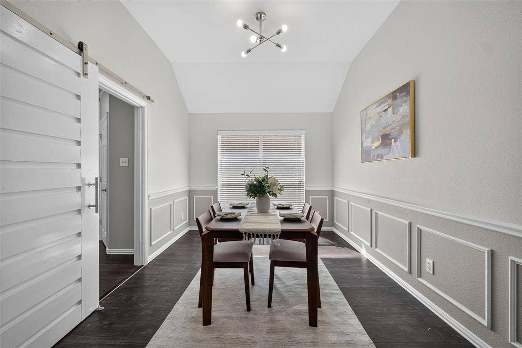 1102 Hartman Court, Arlington, TX 76006 Vaulted ceiling with an updated lighting fixture, wood-finish flooring, half-wall wainscoting, and a window with horizontal blinds