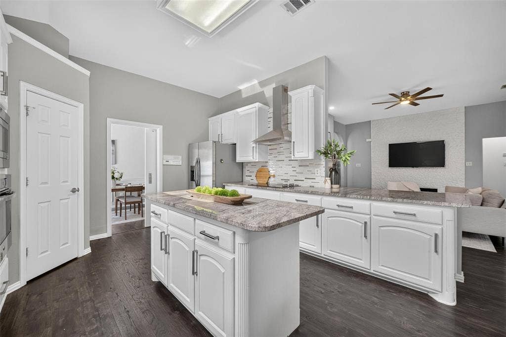 1102 Hartman Court, Arlington, TX 76006 Kitchen featuring white cabinetry, stone countertops, stainless steel appliances, a tile backsplash, and wood-finish flooring