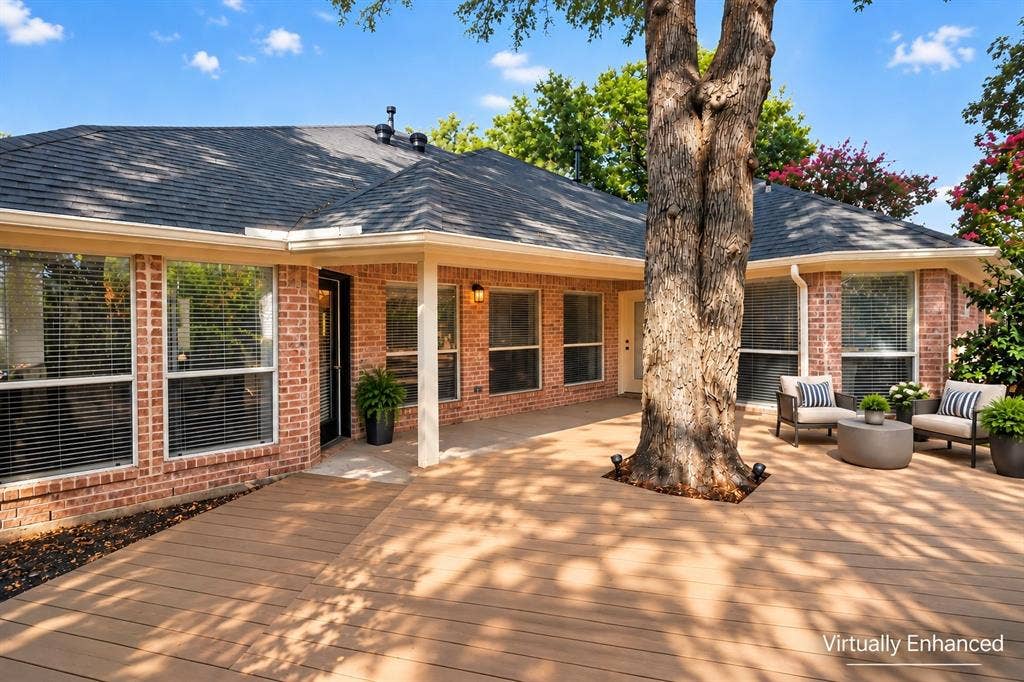 1102 Hartman Court, Arlington, TX 76006 Expansive composite deck, red brick exterior, multiple large windows, covered patio area, and mature trees