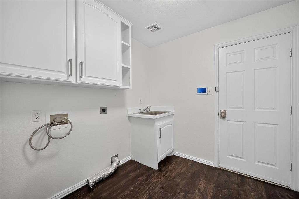 1102 Hartman Court, Arlington, TX 76006 White cabinetry with brushed nickel hardware, utility sink, dark wood-finish flooring, and white paneled door