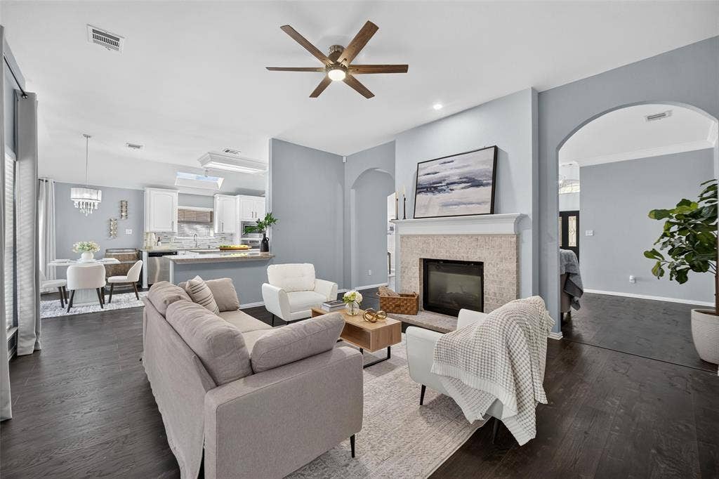 1102 Hartman Court, Arlington, TX 76006 Living area featuring dark wood-finish flooring, a ceiling fan, and a fireplace with a stone surround