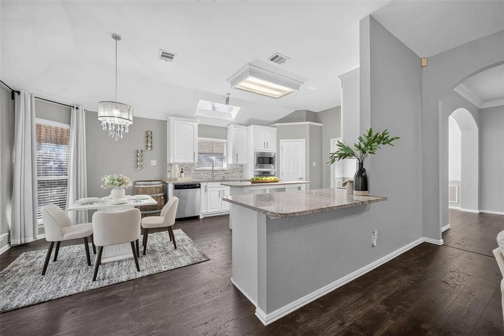 1102 Hartman Court, Arlington, TX 76006 Updated kitchen featuring white cabinetry, stainless steel appliances, and a granite-finish island