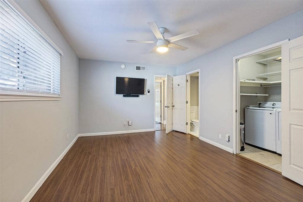 10207 Regal Oaks Drive, #210, Dallas, TX 75230 Wood-finish flooring with white baseboards, window with horizontal blinds, ceiling fan with integrated lighting, and a laundry closet featuring a washer and dryer