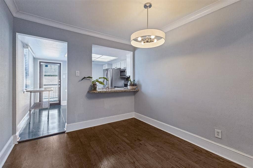 10207 Regal Oaks Drive, #210, Dallas, TX 75230 Wood-finish flooring, crown molding, and a modern chandelier