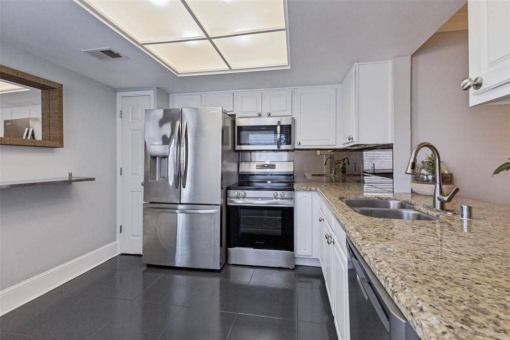 10207 Regal Oaks Drive, #210, Dallas, TX 75230 Kitchen featuring white cabinetry, a double basin stainless steel sink, stainless steel appliances, and granite-style countertops