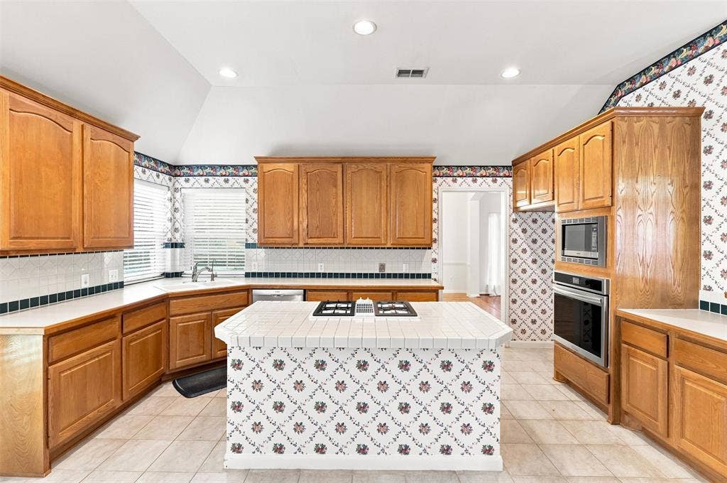 3617 Mackenzie Lane, Richardson, TX 75082 Kitchen featuring wood cabinetry, white tile countertops, a built-in oven, built-in microwave, and a center island with gas cooktop.