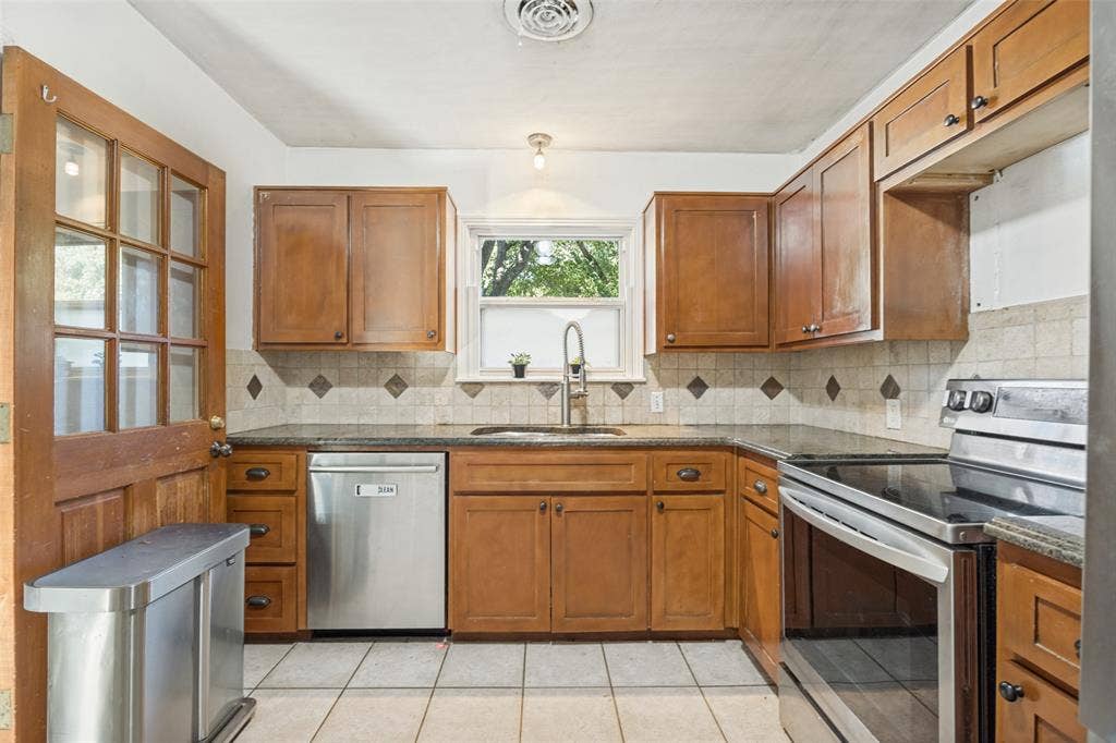 559 Blanning Drive, Dallas, TX 75218 Kitchen featuring wood cabinetry, SS appliances, plumbed for gas, electric induction cooktop, convection oven, and regular oven all in one, granite-style countertops, tile flooring, and tumbled marble backsplash