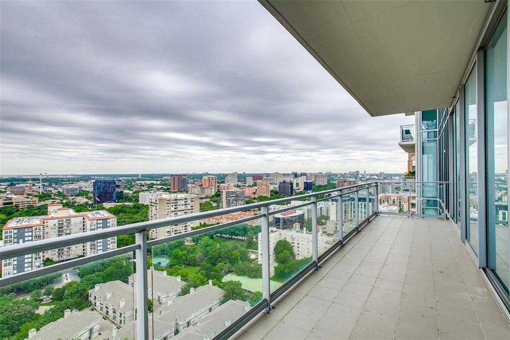 Expansive balcony featuring a glass railing, neutral tile flooring, and large sliding glass doors