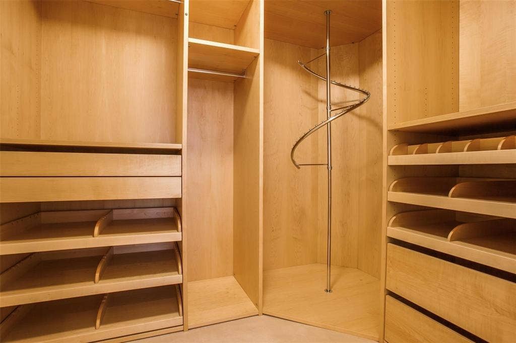 Built-in closet system featuring natural wood-finish cabinetry, integrated drawers, adjustable shelving, and a spiral garment rack