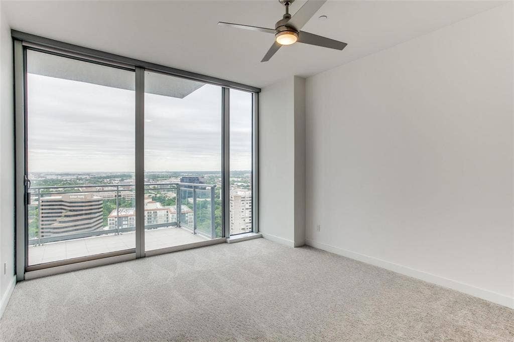 Expansive floor-to-ceiling windows, private balcony, and contemporary ceiling fan with integrated lighting