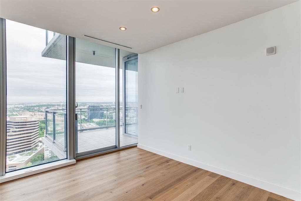 Floor-to-ceiling windows, wood-finish flooring, recessed ceiling lighting, and a private balcony with glass railings