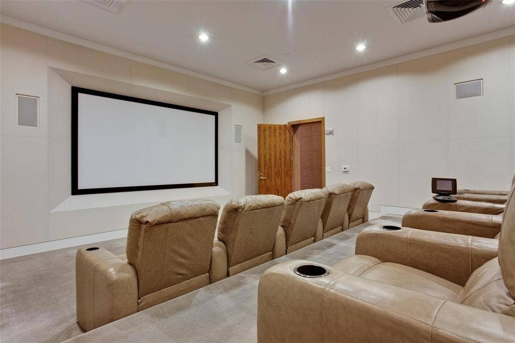 Dedicated media room with a large projection screen, recessed ceiling lighting, and built-in wall speakers