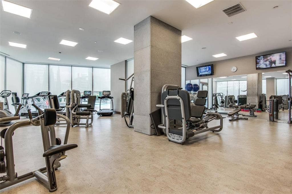 Fitness center featuring comprehensive exercise equipment, full-height windows, recessed lighting, and wall-mounted televisions