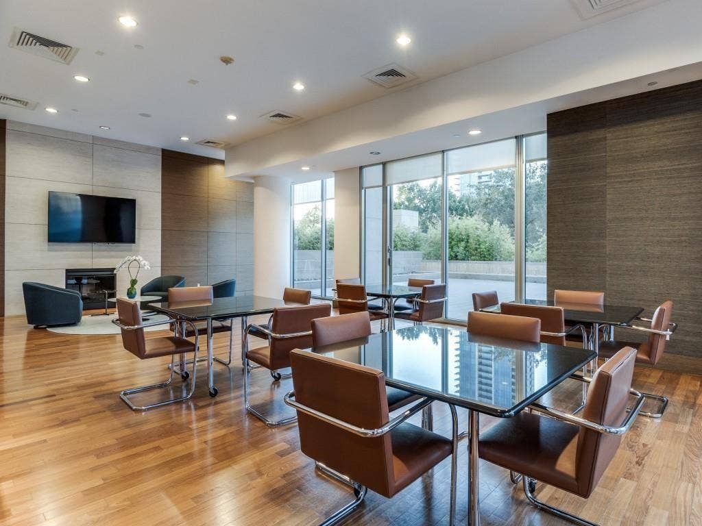 Hardwood flooring, recessed lighting, fireplace with stone surround, full height windows, and a textured accent wall
