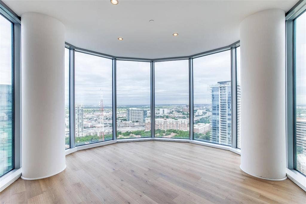 Expansive floor-to-ceiling windows, wood-finish flooring, recessed lighting, and curved architectural columns