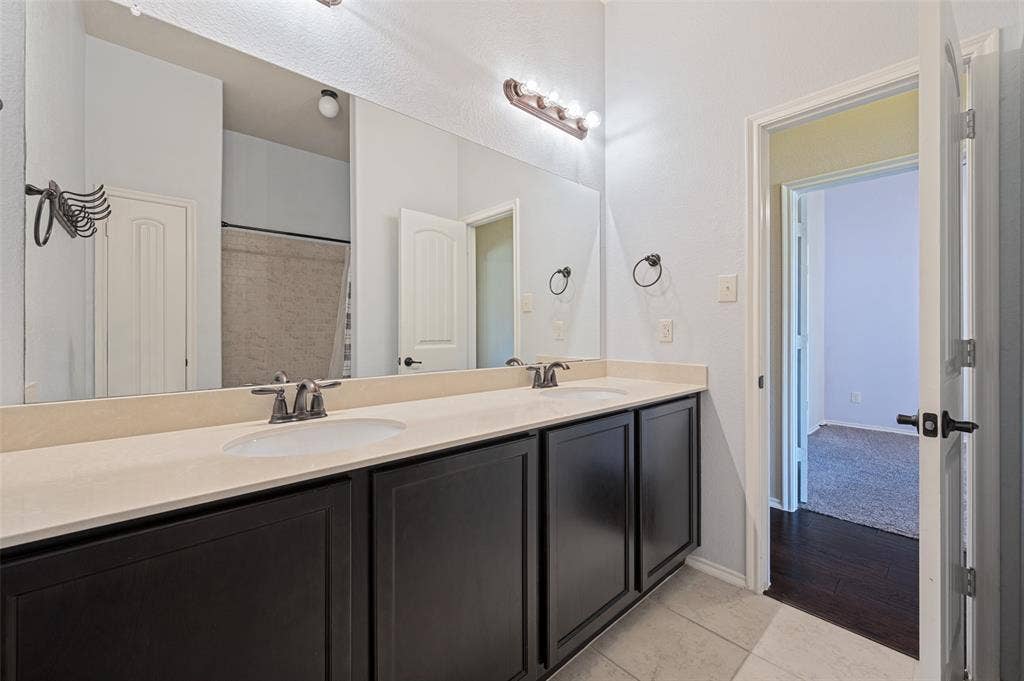 Dual vanity with integrated sinks, light-toned countertop, and dark wood-finish cabinetry
