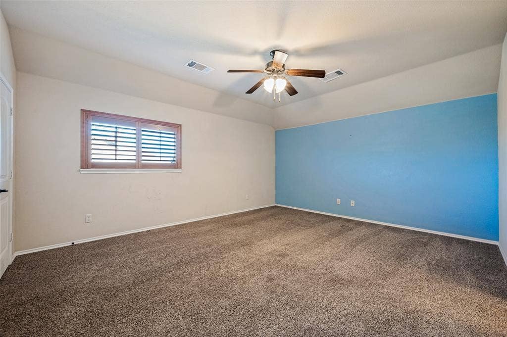 Carpeted room featuring a ceiling fan with light, a window with horizontal blinds, and a distinctive accent wall