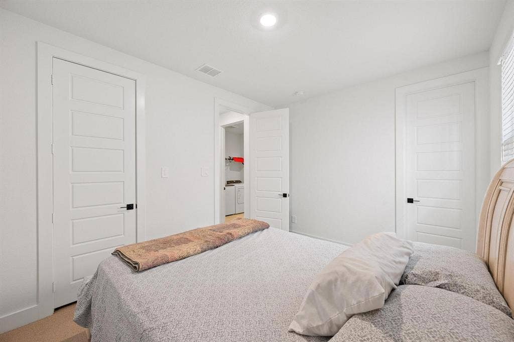 White interior doors with black hardware, white walls, recessed ceiling lighting, and carpet flooring