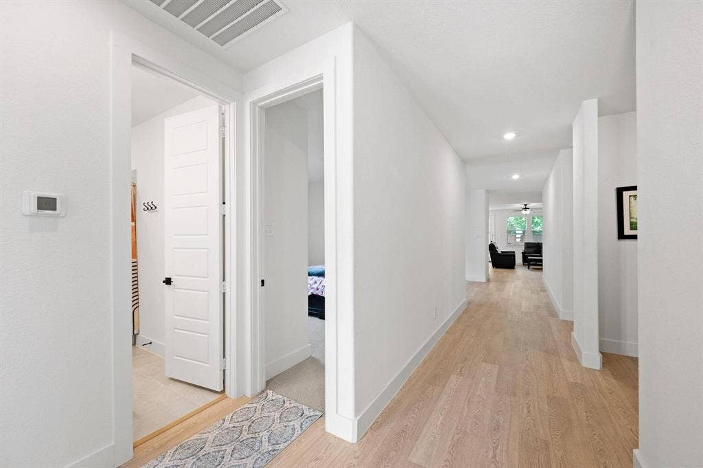 Hallway with light wood-finish flooring, recessed lighting, and white panel doors