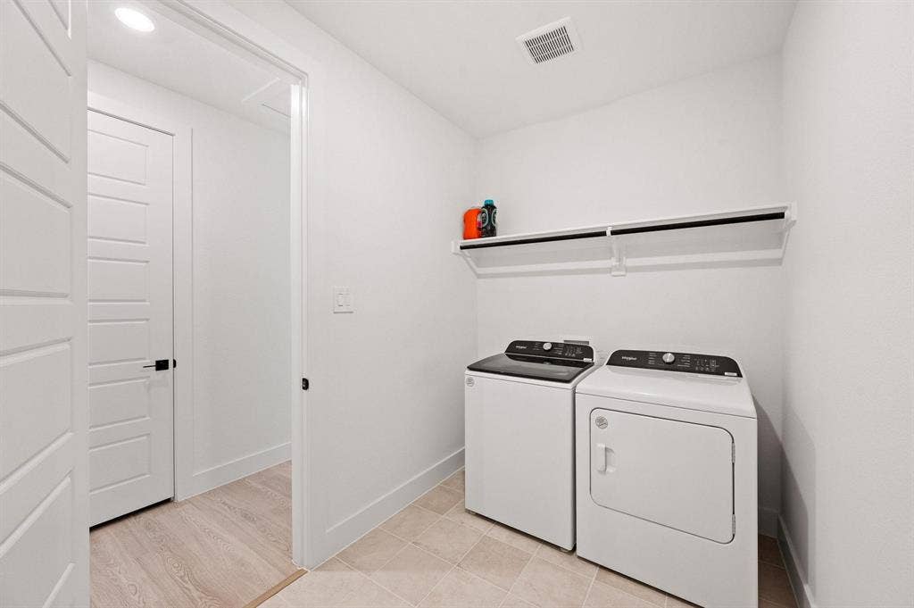 Dedicated laundry space featuring a built-in shelf, light-toned tile flooring, and recessed lighting